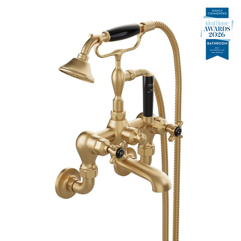 Booth & Co. Axbridge wall mounted bath shower mixer tap with shower kit and cross handles, finished in brushed brass with black ceramic accents.