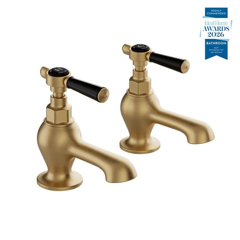 Booth & Co. Axbridge bath pillar taps with lever handles, finished in brushed brass with black ceramic accents.