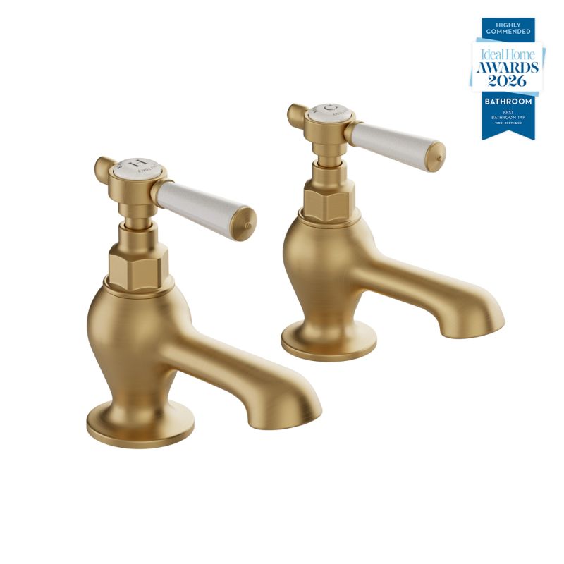 Booth & Co. Axbridge bath pillar taps with lever handles, finished in brushed brass with crackled off-white ceramic accents.