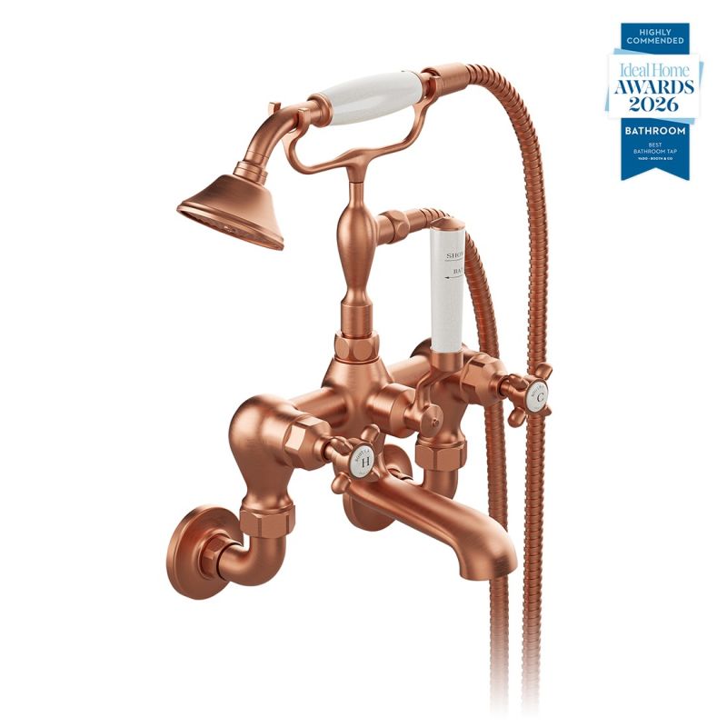 Booth & Co. Axbridge wall mounted bath shower mixer tap with shower kit and cross handles, finished in brushed brass with black ceramic accents.