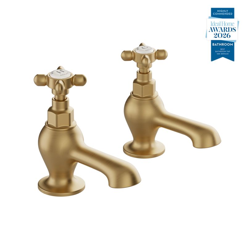 Booth & Co. Axbridge bath pillar taps with cross handles, finished in brushed brass with crackled off-white ceramic accents.
