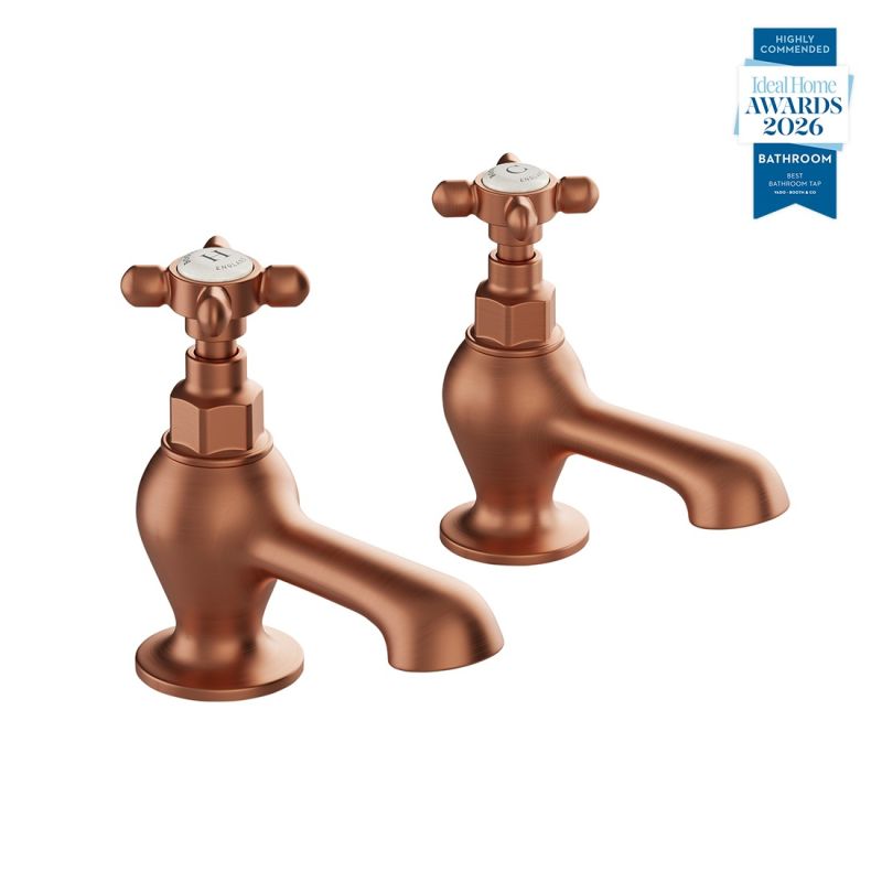 Booth & Co. Axbridge bath pillar taps with cross handles, finished in brushed brass with black ceramic accents.