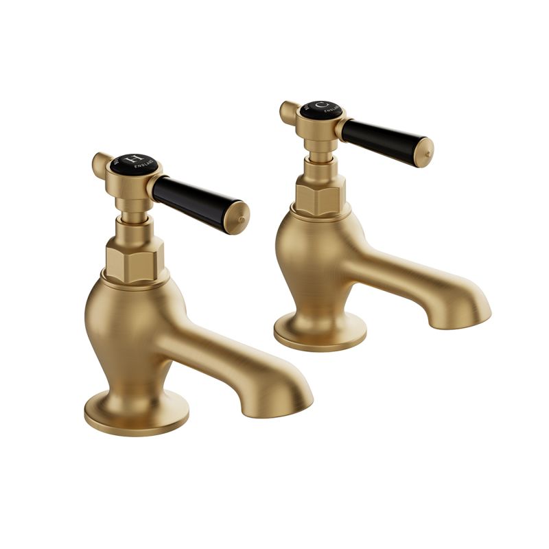 Booth & Co. Axbridge bath pillar taps with lever handles, finished in brushed brass with black ceramic accents.
