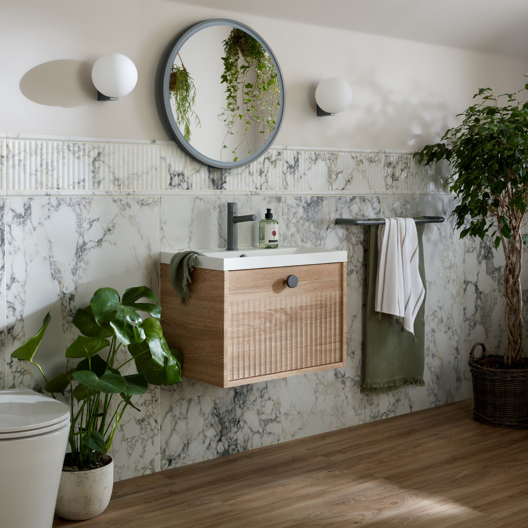 Fluted natural oak wall hung vanity, with black brassware. Round wall hug LED mirror with pedant lighting